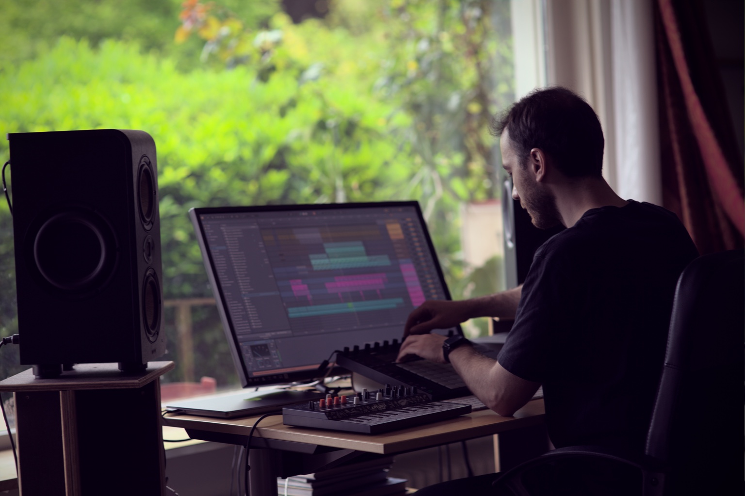 Jonas Mondello making music at his studio desk beside a window